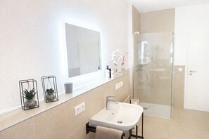 A modern bathroom with a large mirror, a sink, and a glass-enclosed shower. - Gästehaus Jekle – Zimmer & Ferienwohnungen (Neuburg an der Kammel)