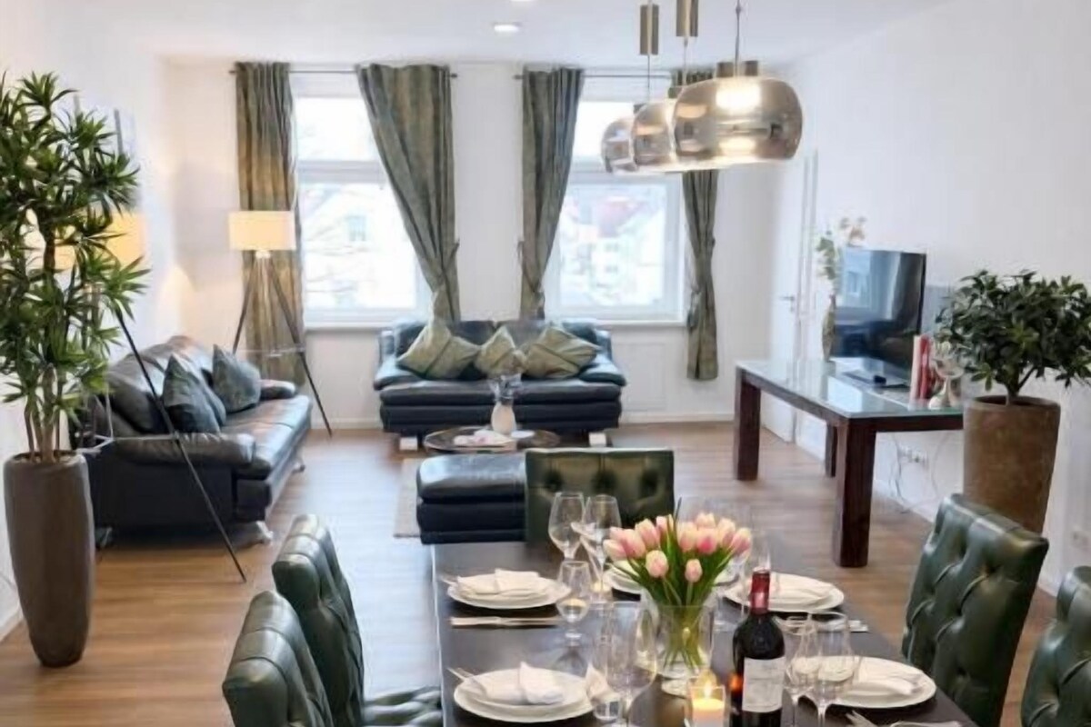 A dining area with a table set for four, surrounded by green upholstered chairs.