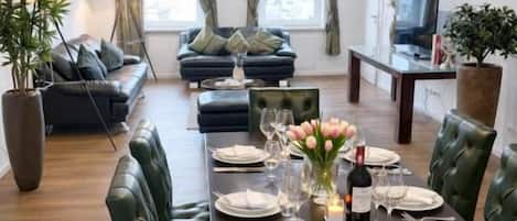 A dining area with a table set for four, surrounded by green upholstered chairs.