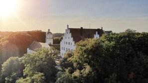 A historic building with a prominent tower and a steeply pitched roof, surrounded by dense foliage. - Gästehaus Jekle – Zimmer & Ferienwohnungen (Neuburg an der Kammel)