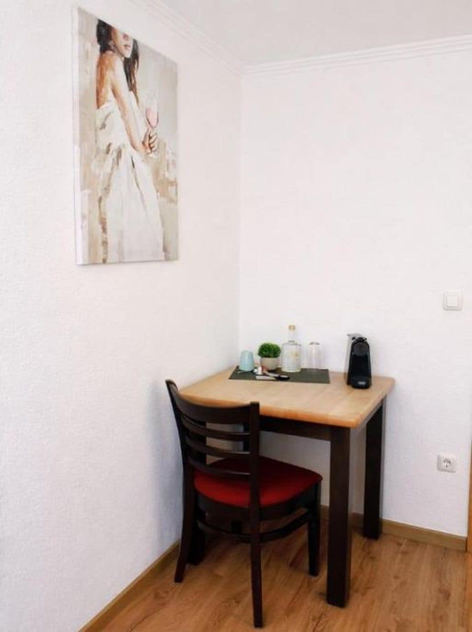 Ein kleiner Essbereich mit einem Tisch, einem Stuhl und einem Bild an der Wand.