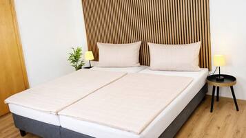 A double bed with a wooden headboard, two bedside tables with lamps, and a small plant on the nightstand.