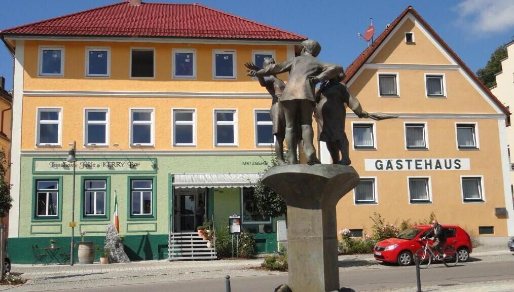 Un bâtiment avec une enseigne indiquant « GÄSTEHAUS » et une statue devant.