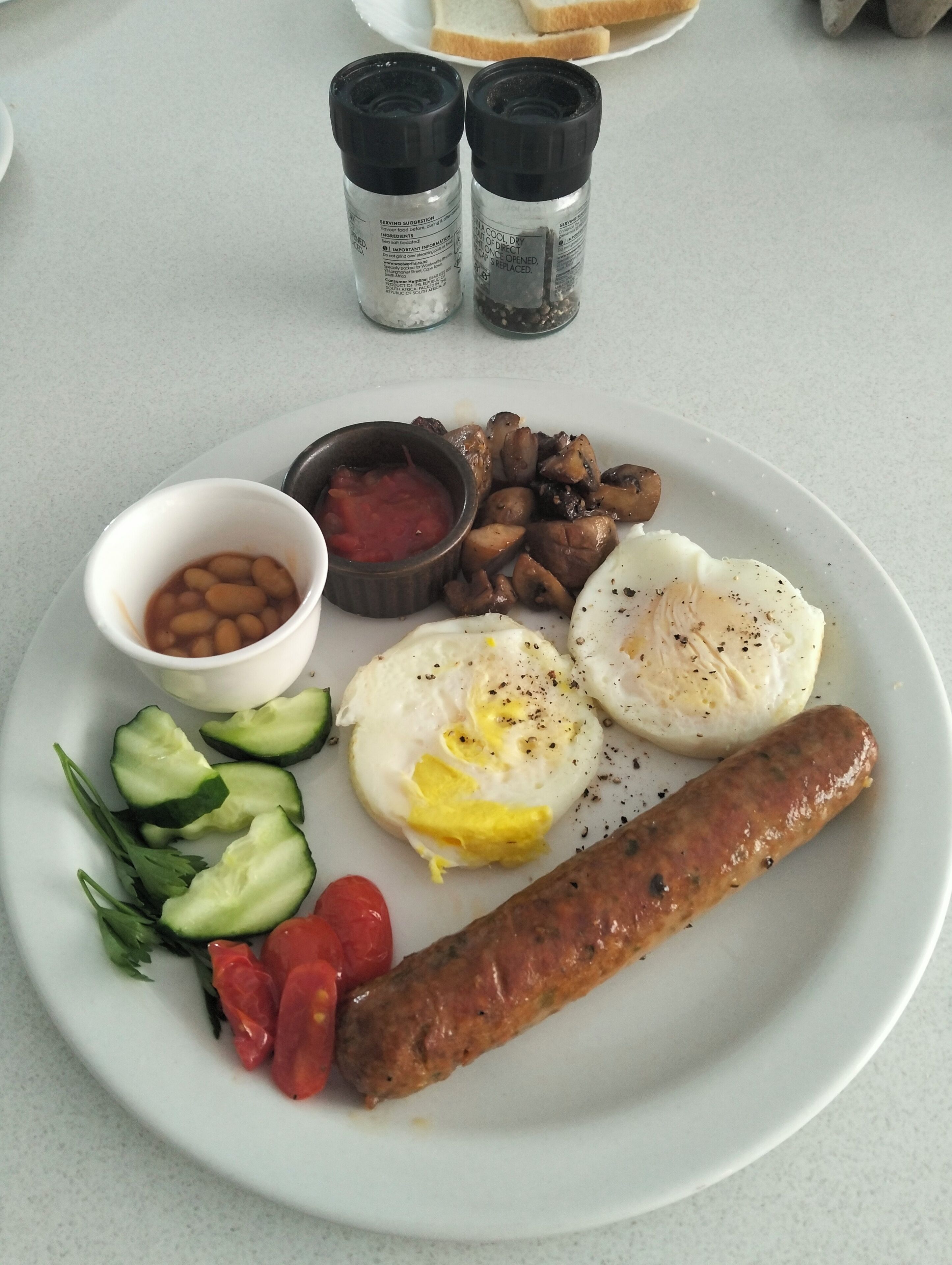 En tallerken med æg, pølse, bønner, svampe og grøntsager.