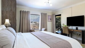 Une chambre d’hôtel avec un grand lit, un bureau doté d’un téléviseur à écran plat, une lampe et une vue sur l’extérieur par la fenêtre.