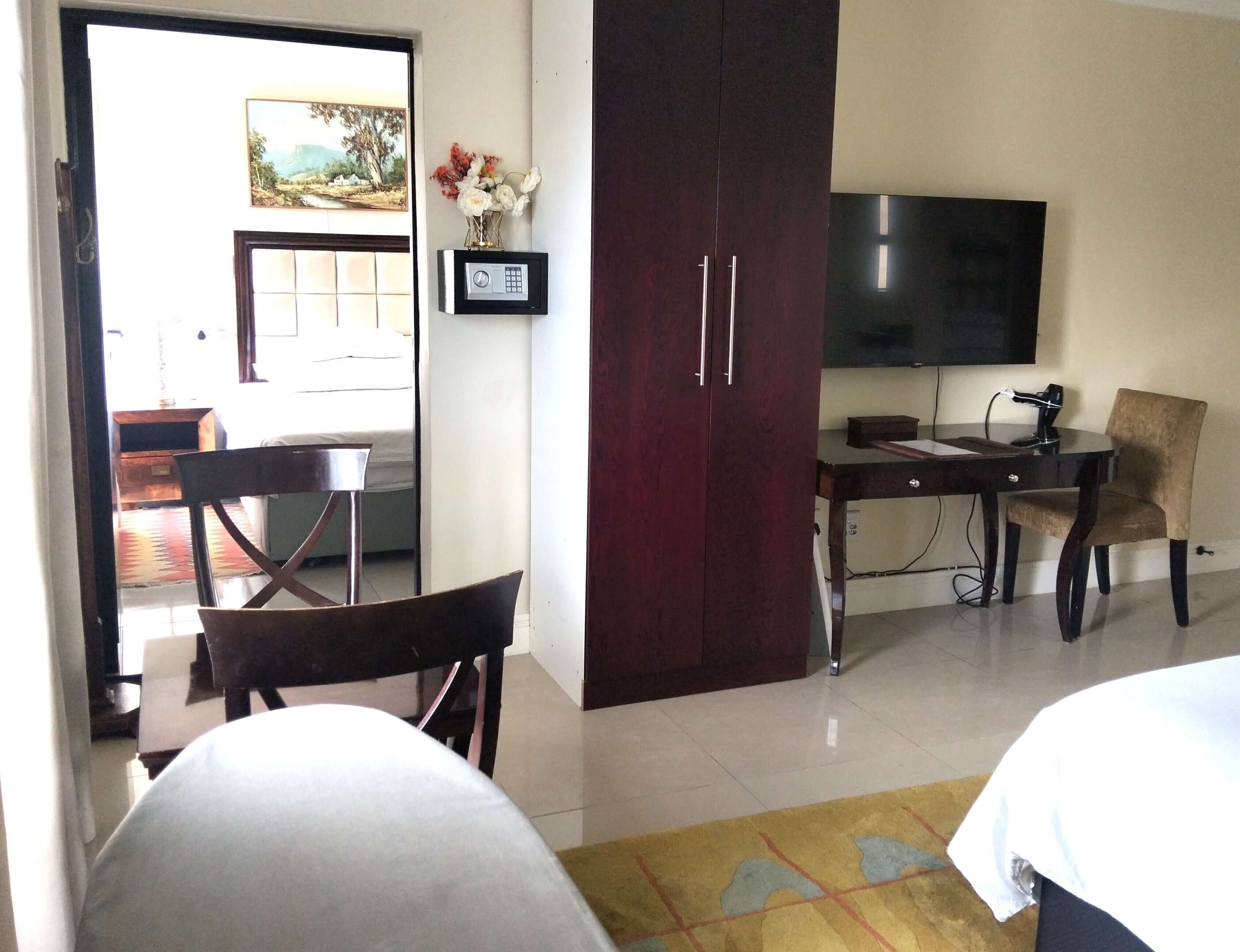 Una habitación de hotel con cama, escritorio, silla, televisor y armario.
