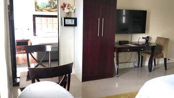 Una habitación de hotel con cama, escritorio, silla, televisor y armario.