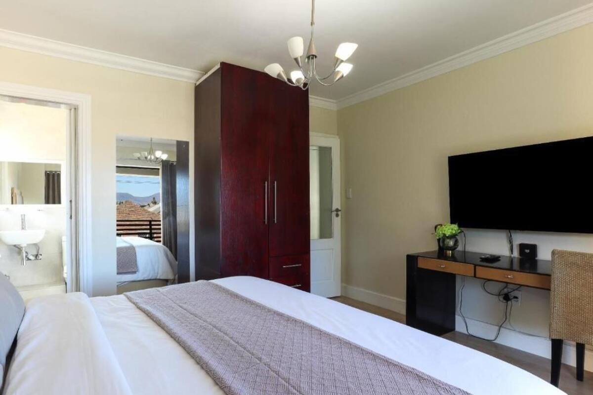 Un dormitorio con una cama grande, un escritorio, una silla, un televisor y un armario.