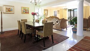 Un coin repas avec une grande table et des chaises, un lustre et un canapé à motifs zébrés en arrière-plan.