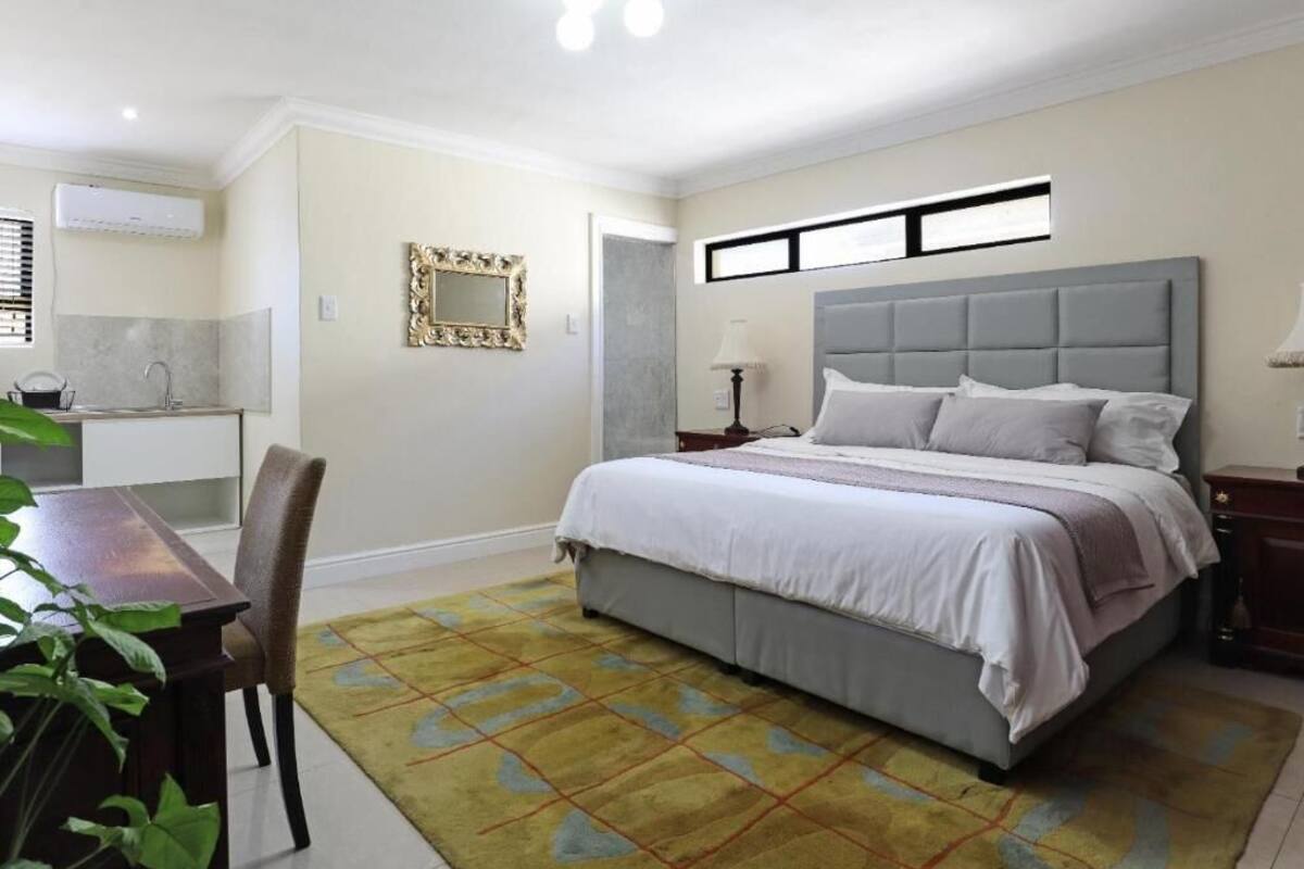 Un dormitorio con cama, mesita de noche, lámpara y una pequeña mesa con sillas.