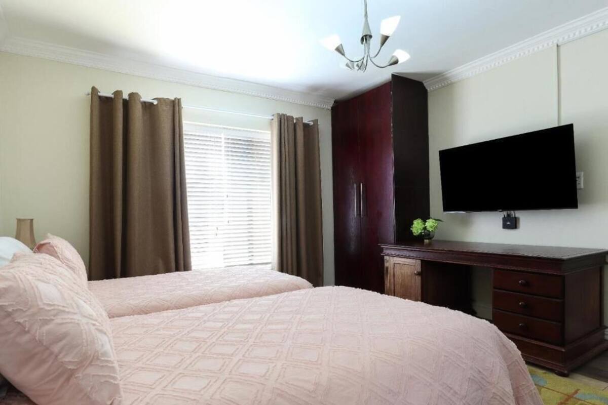 Habitación de hotel con dos camas, televisión, armario y ventana con cortinas.