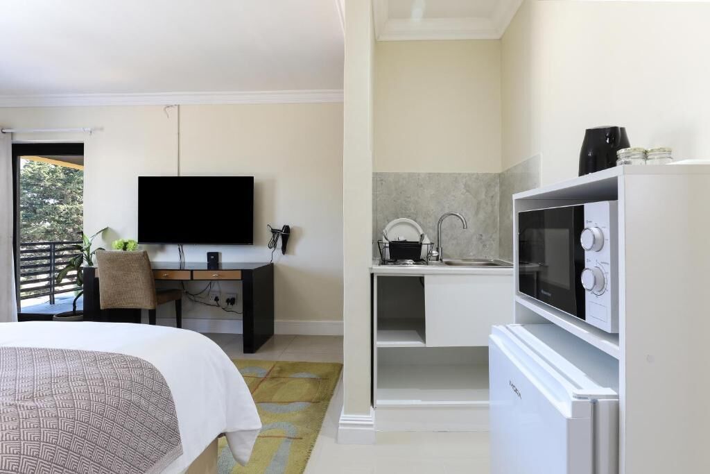 Een hotelkamer met een bed, een televisie, een bureau, een magnetron en een koelkast.