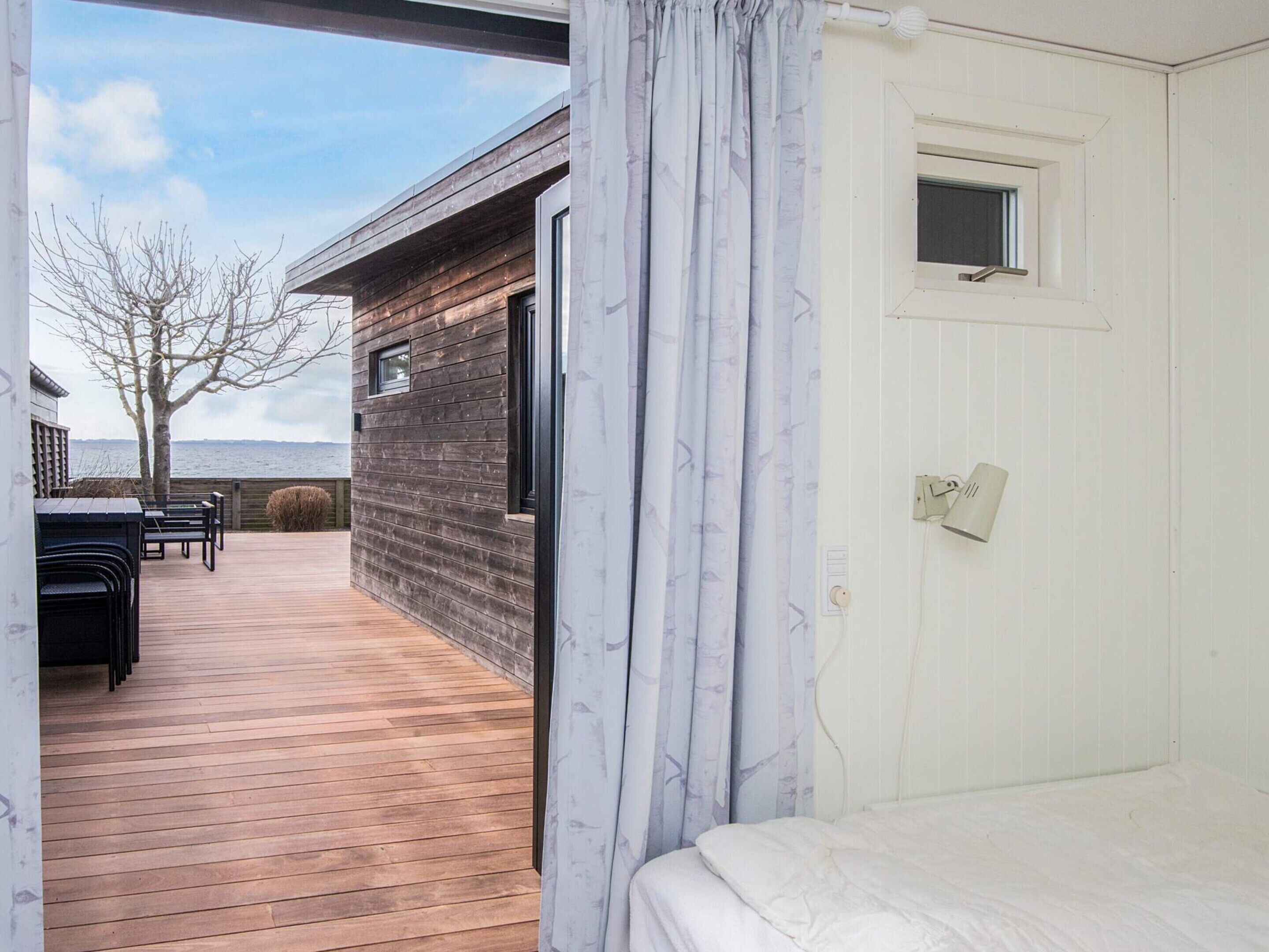 A bedroom with a wooden deck, a view of the sea, and a small window.
