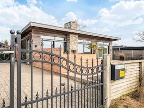 A modern house with a stone chimney, a wooden deck, and a metal gate. - 4 Star Holiday Home in Ronde (Ronde)