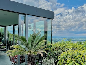 Ein modernes Gebäude mit großen Glasfenstern, Landschaftsblick und verschiedenen Pflanzen.