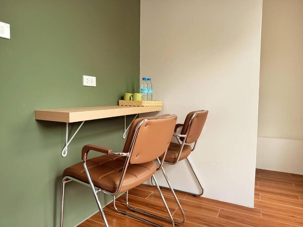 A room with two brown leather chairs, a wooden shelf with water bottles, and a green wall.