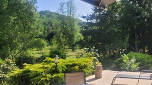 An outdoor patio with a round table and chairs, surrounded by lush greenery and trees. - Equestrian Retreat in the Forest with Donkeys – Domaine L'échappée Verte (Soucht)