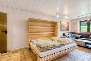 Un dormitorio moderno con una cama de madera, un sofá y un ventanal grande.