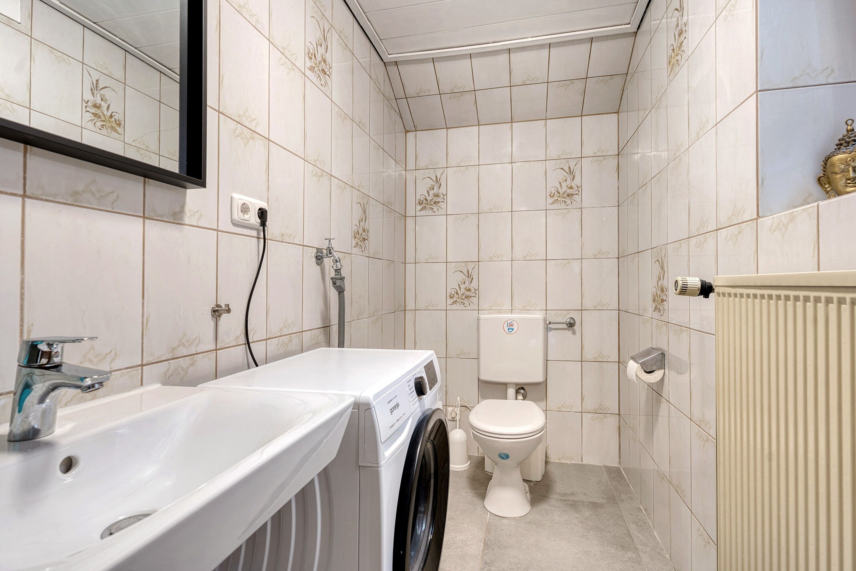 Un baño pequeño con lavadora, inodoro y radiador.