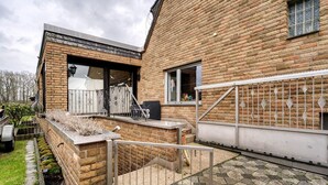 A brick house with a patio, a metal gate, and a small garden area. - Holiday Apartment Am Linnert with Shared Terrace, Garden, and Wi-Fi (Haltern am See)