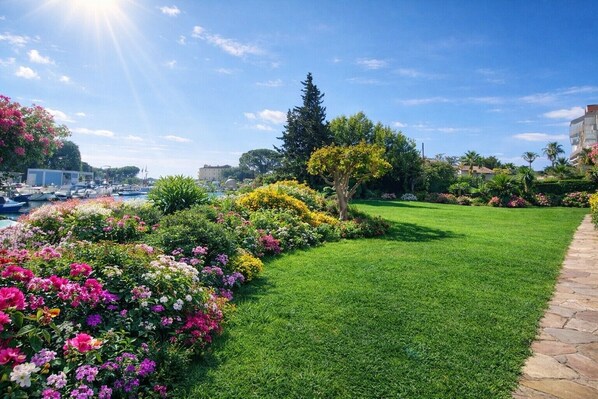 Un jardin bien entretenu, agrémenté de nombreuses fleurs aux couleurs vives et d’une pelouse parfaitement taillée, le tout bordé d’un sentier en pierre.