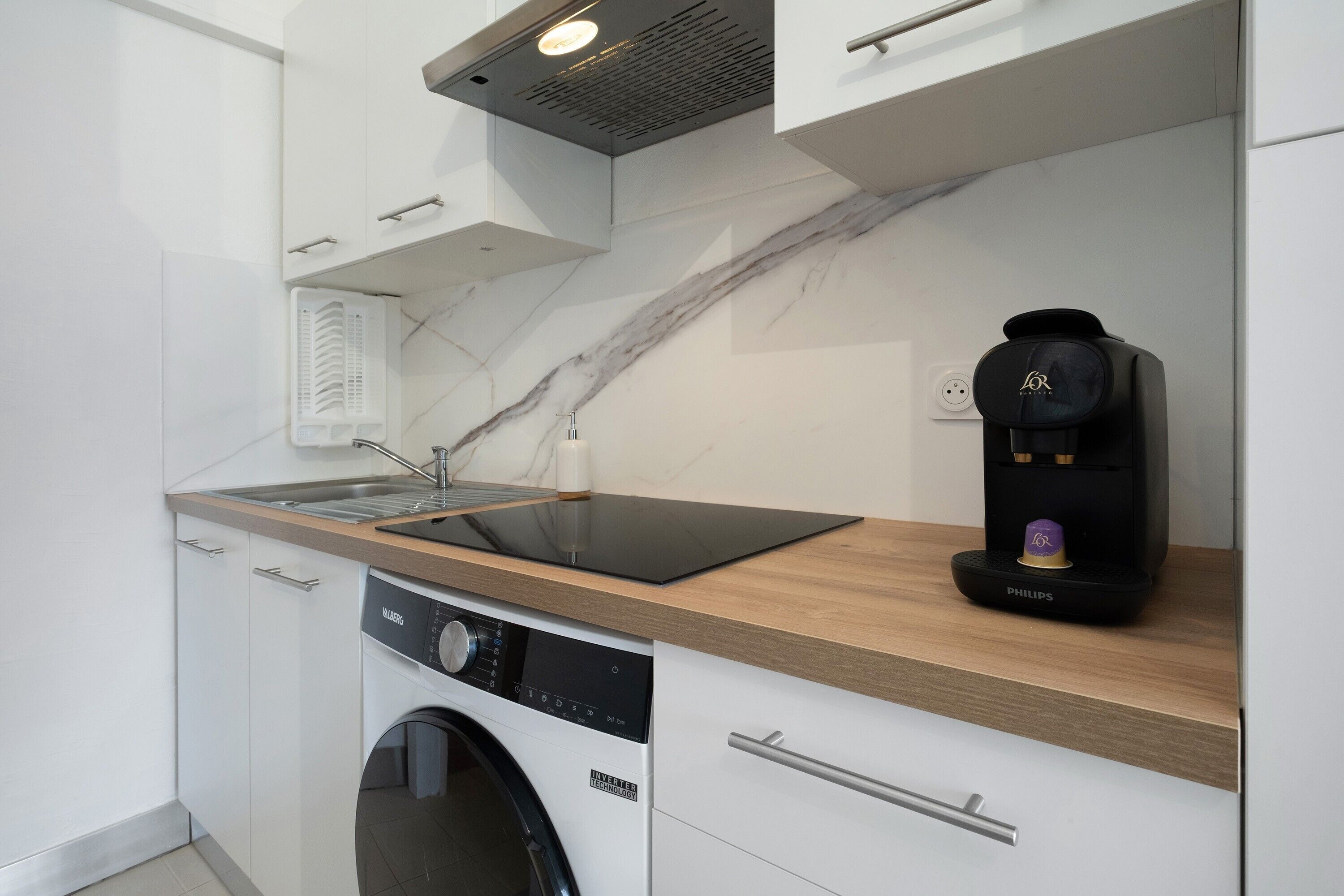 A modern kitchen with a built-in dishwasher, a coffee machine, and a marble backsplash.