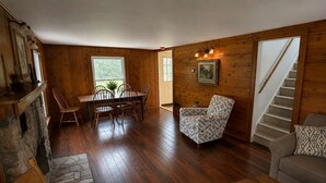 Un intérieur en bois comprenant une table à manger, des chaises, un fauteuil à motifs, un canapé et un escalier.