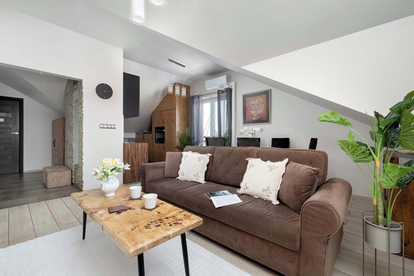 A wide shot of the living room with the sofa, coffee table, and TV visible. Skylights bring in natural light, enhancing the airy feel.