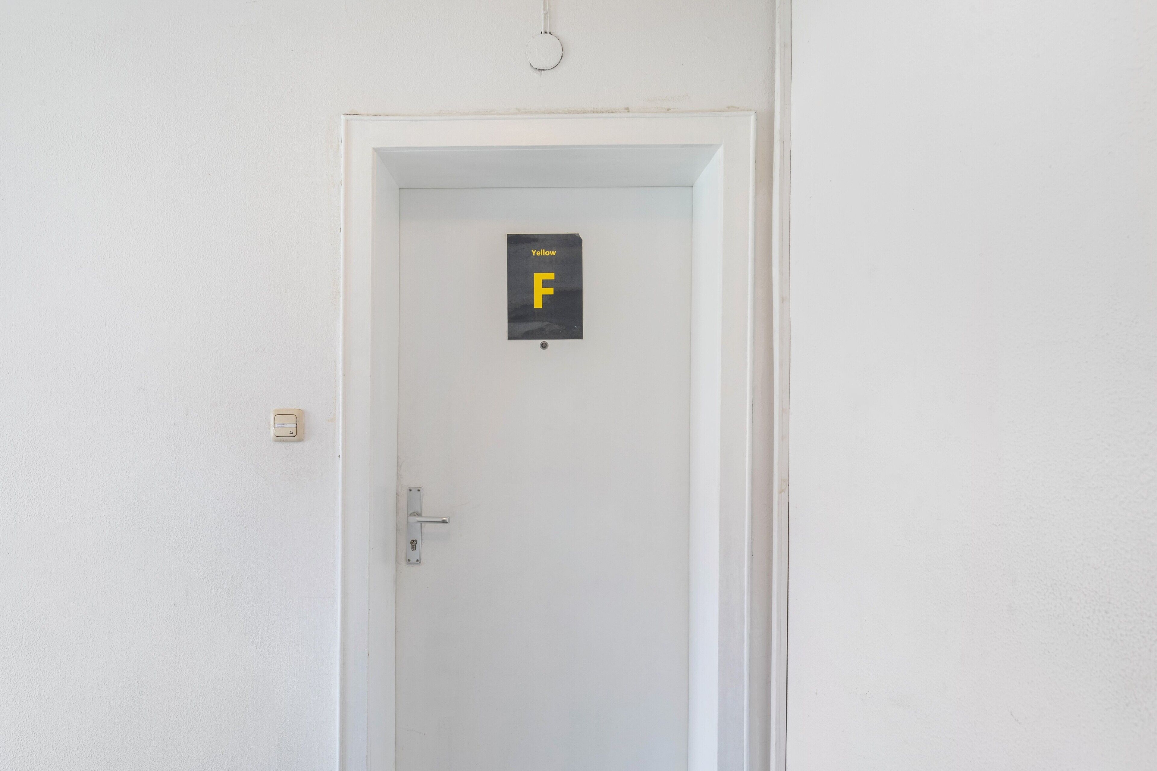 Eine weiße Tür mit einem Schild mit dem Schriftzug 'Yellow F'.