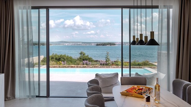 A modern room with a large sliding glass door leading to a pool and a view of the sea. - The Palms Resort Villa President Two with Pool (Tkon)