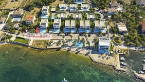 An aerial view of a coastal resort with multiple villas, a swimming pool, and a marina. - The Palms Resort Villa President Two with Pool (Tkon)