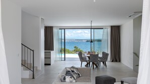 A modern living room with a dining area, large windows, and a view of the sea. - The Palms Resort Villa President Two with Pool (Tkon)