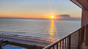 A balcony with a view of the ocean at sunset, a swimming pool, and a building structure. - Myrtle Beach Resort RT1915 (Myrtle Beach)