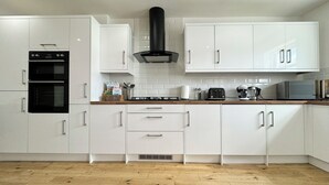 A modern kitchen with white cabinets, a black range hood, and a wooden countertop. - The Kipling Inn, 4 - Bed, Sleeps 6, Long Term Rental Available (Ulverston)