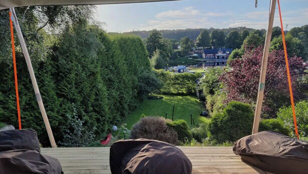 A wooden deck with two bean bags and a swing. A view of a green landscape with trees and houses is visible through the foliage. - Cozy house 600 meters from the city center, view of the water and beautiful nature (Halmstad)