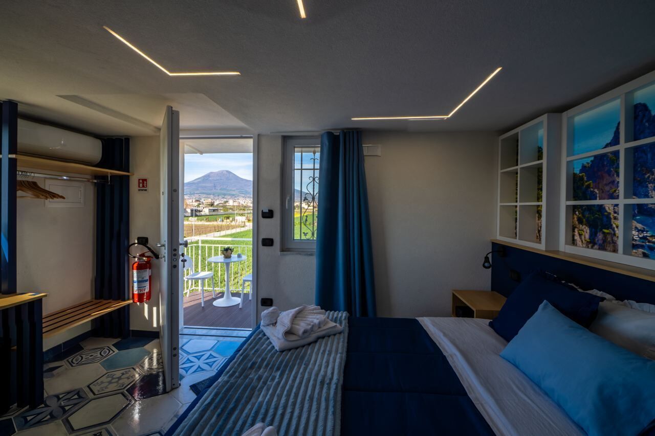 Habitación de hotel moderna con una cama, vista a la montaña y un balcón con mesa y sillas.