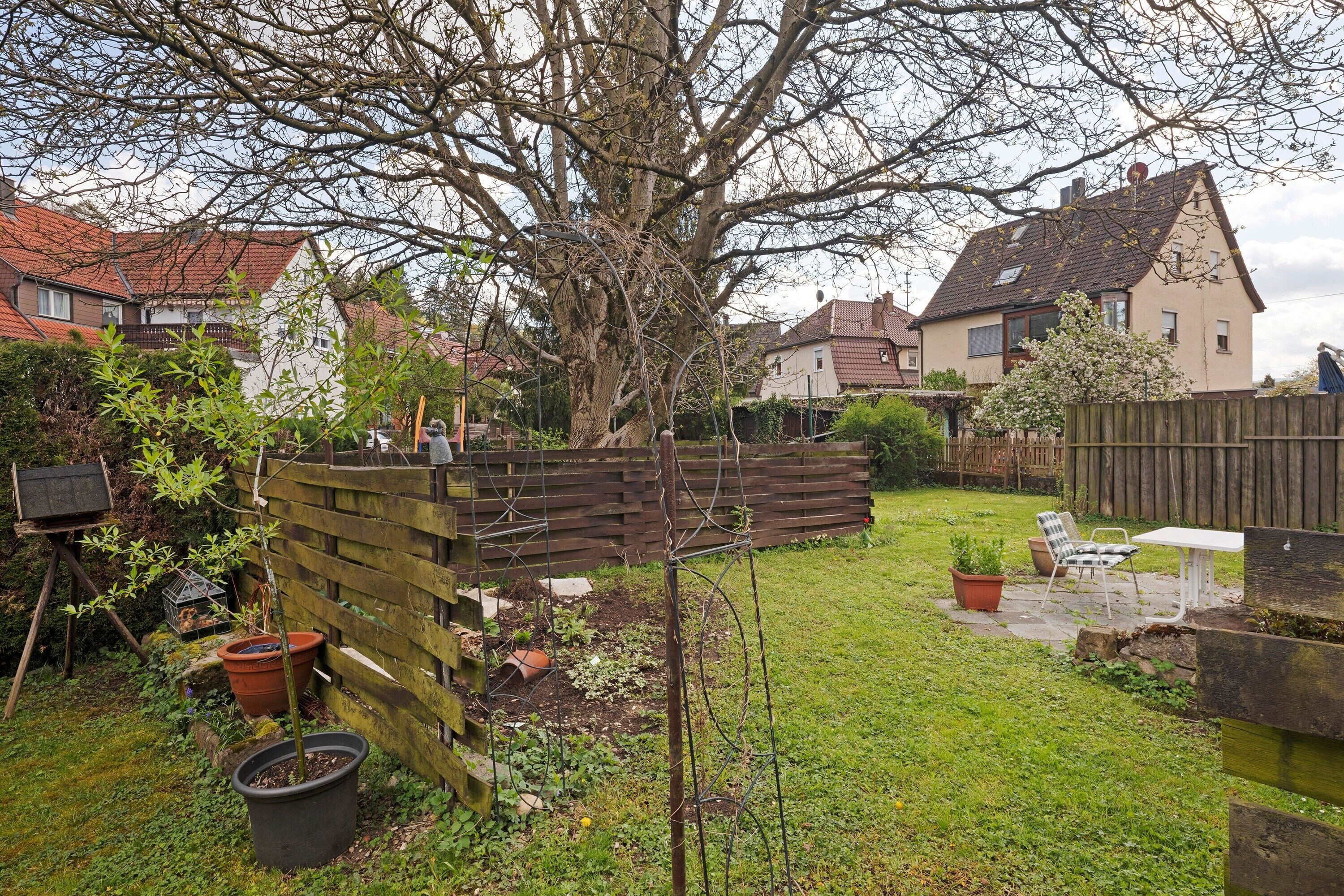 A residential backyard with a wooden fence, a tree, and a garden area.