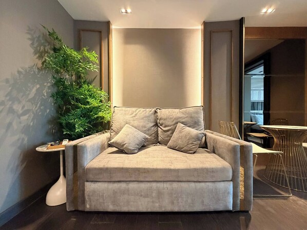 A modern living room with a beige sofa, a side table, and a potted plant.