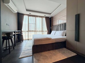 A modern hotel room with a large bed, a desk, and a chair.