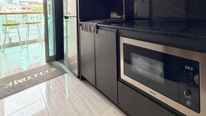 A modern kitchen with dark cabinetry, a stainless steel oven, and a glass door. - Room-luxury Condo, Chaing Mai Night Baza (Chiang Mai)