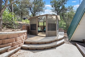 A covered outdoor seating area with a glass enclosure, surrounded by a stone retaining wall and a wooden deck. - Zion's Emerald| Walk into East Zion| Amazing Stars (Orderville)