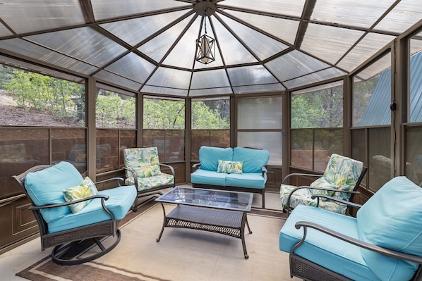 A sunroom with a glass ceiling, blue cushioned chairs, and a glass coffee table. - Zion's Emerald| Walk into East Zion| Amazing Stars (Orderville)