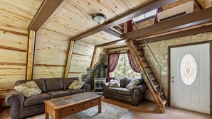 Ein gemütliches Blockhaus-Interieur mit zwei Sofas, einem Holztisch und einem Steinkamin.