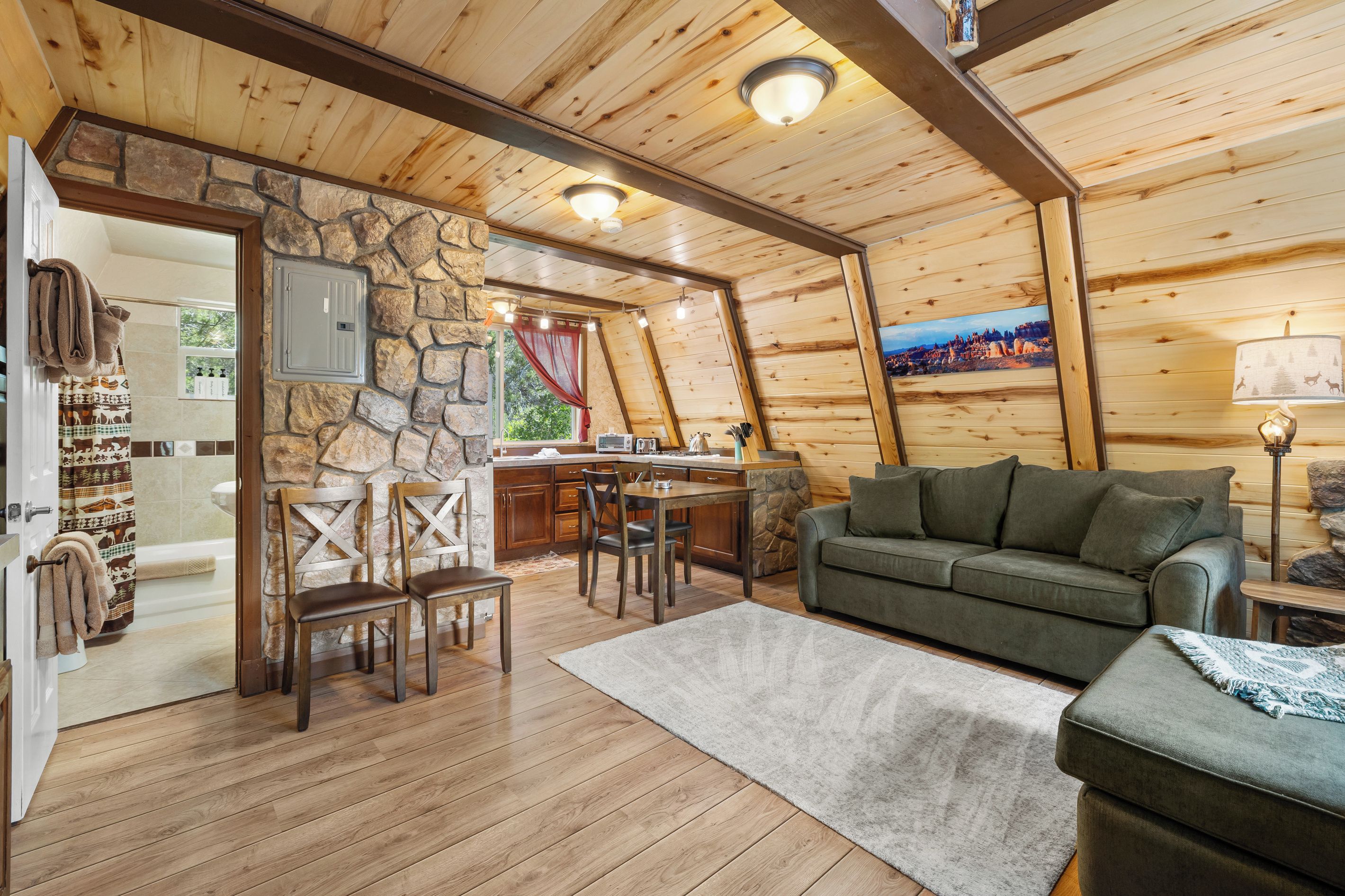 Ein gemütliches Blockhaus-Interieur mit einer Steinwand, Holzmöbeln und Blick auf eine Berglandschaft.