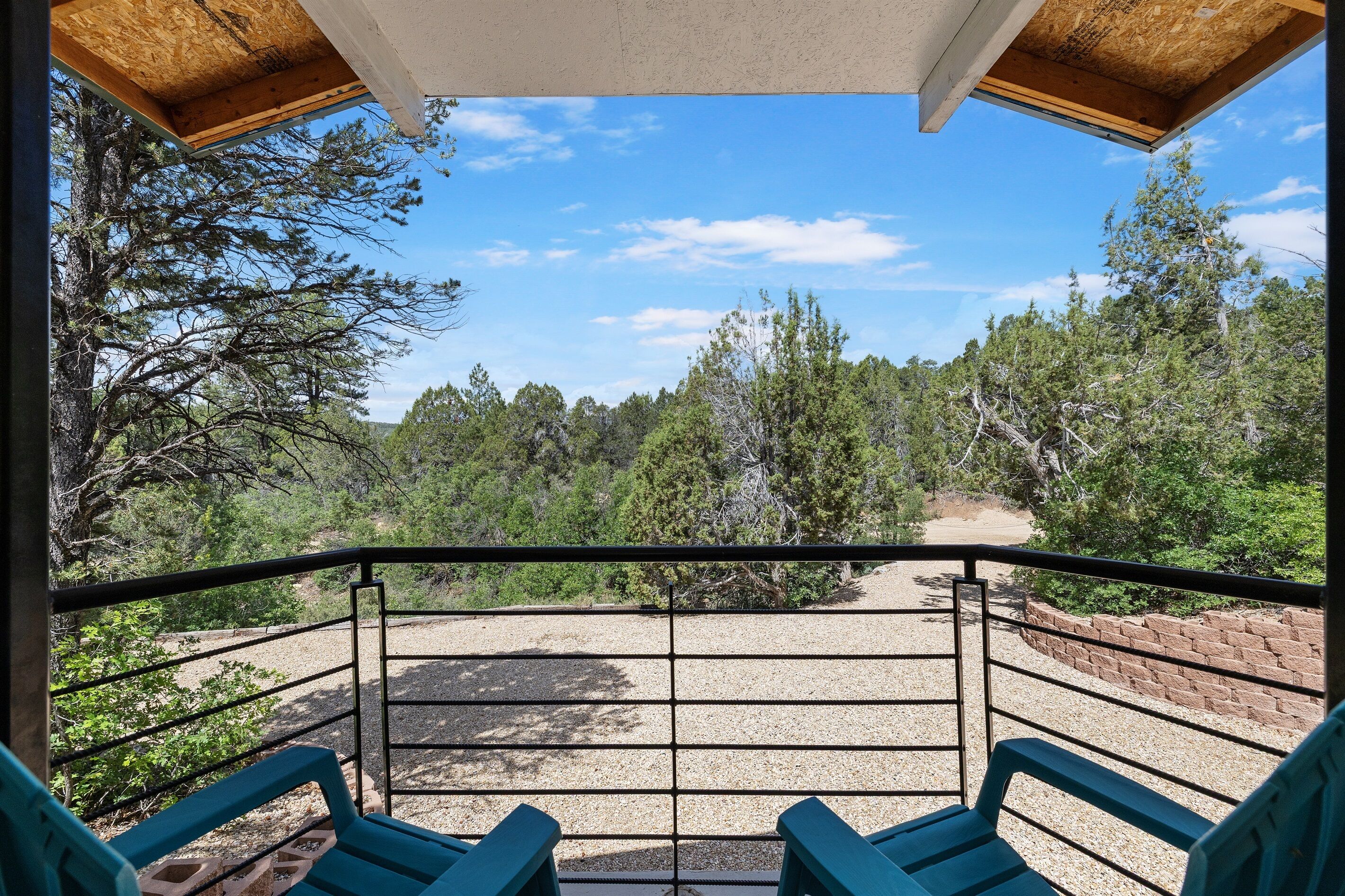 A balcony with a view of a forested area and a gravel path.