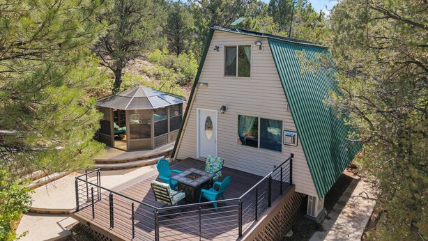 Eine Holzhütte mit einer Terrasse, Sitzgelegenheiten im Freien und einer überdachten Veranda.