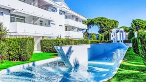A modern hotel with a swimming pool, lush greenery, and a clear blue sky. - Green Club by Interhome (Pals)