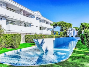 A modern hotel with a swimming pool, lush greenery, and a clear blue sky. - Green Club by Interhome (Pals)