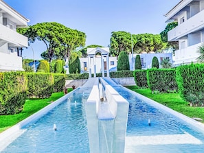 A modern hotel with a central water feature, symmetrical landscaping, and white buildings. - Green Club by Interhome (Pals)