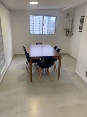 A dining area with a table and chairs, a window with a view of buildings, and a wall-mounted air conditioner. - Spacious 4-bedroom apartment in terrific Balneário Camboriú with AC (Balneário Camboriú)